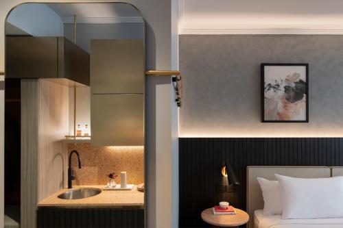 - une chambre avec un lit, un lavabo et un miroir dans l'établissement The Sebel Sydney Martin Place, à Sydney