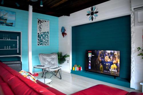 a living room with a couch and a flat screen tv at Sotoura Beach House Shimoda - Less thank 1 min walk to Sotoura Beach! in Shimoda