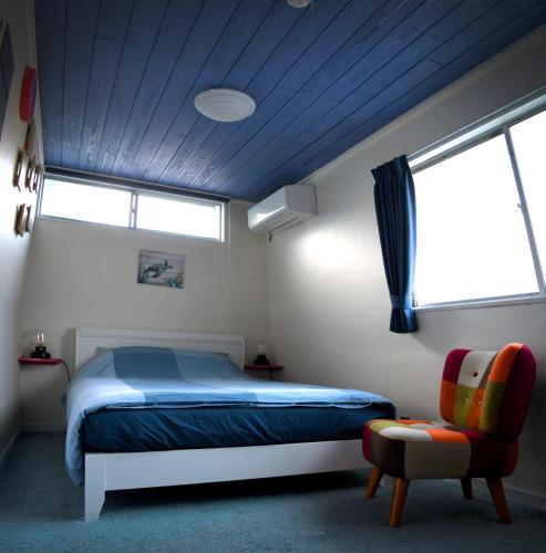 a bedroom with a bed and a window and a chair at Sotoura Beach House Shimoda - Less thank 1 min walk to Sotoura Beach! in Shimoda
