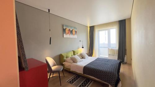 a bedroom with a bed and a chair and a window at 2 room Modern Apartment View in Dnipro