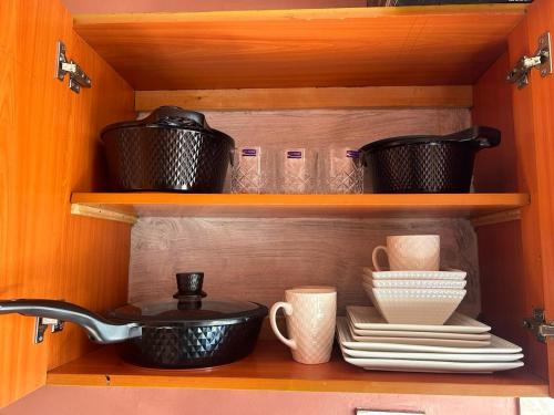 a shelf with pots and pans and plates and cups at Tenet Upper Kabete Homes in Nairobi