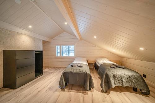 a attic room with two beds and a fireplace at Villa Alvo in Kittilä