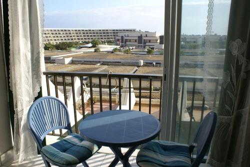 d'un balcon avec une table et des chaises et une vue sur un bâtiment. dans l'établissement Studio 46, Héliopolis FGH au village naturiste, au Cap d'Agde