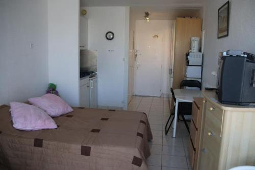 une petite chambre avec un lit et une télévision dans l'établissement Studio 46, Héliopolis FGH au village naturiste, au Cap d'Agde