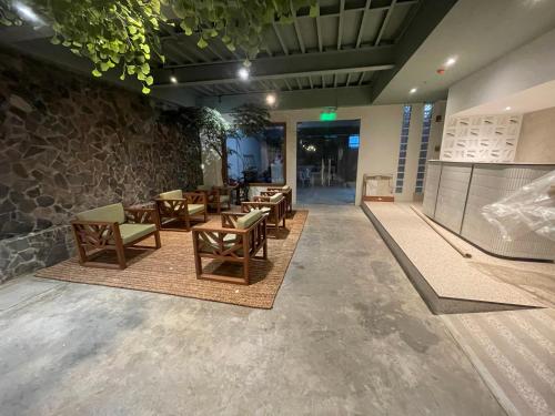 a lobby with tables and chairs and a stone wall at The Millas Hostel in Manila