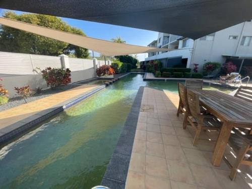a swimming pool with a wooden table and a bench at City Stadium Apartment 3 in Townsville