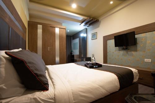 a bedroom with a bed with a television on the wall at Golden Avenue in Trivandrum
