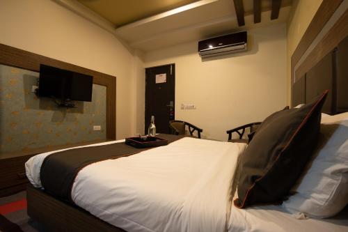 a bedroom with a bed with a tv on the wall at Golden Avenue in Trivandrum