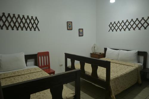 two beds in a room with a white wall at Hotel Las Colinas in Fortuna