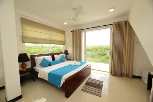 a bedroom with a bed with a large window at Kurulu Villa Baddegama in Galle