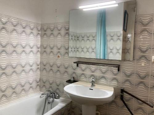 une salle de bain avec un lavabo, un miroir et une baignoire dans l'établissement Appartement 308, Héliopolis K, au Cap d'Agde