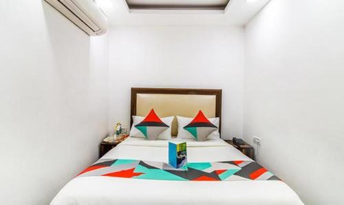 una camera da letto con un grande letto bianco con cuscini colorati di Comfy Stay Hotels a Nuova Delhi