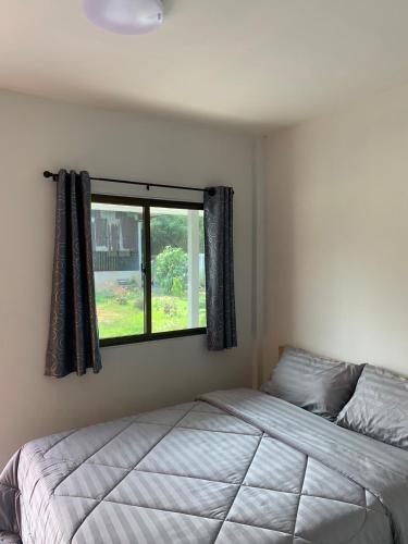 a bedroom with a bed and a window at KHUN CHUAT'S HOUSE in Ban Nong Ben