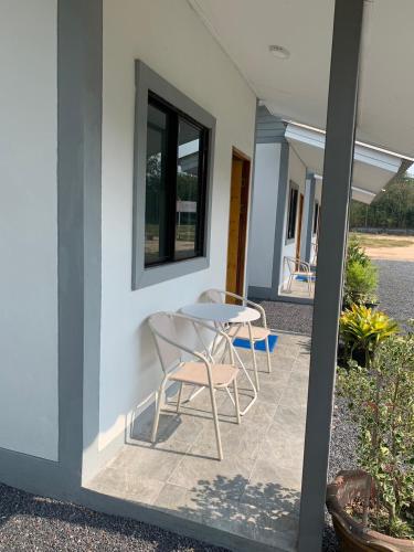 a patio with two chairs and a table next to a building at KHUN CHUAT'S HOUSE in Ban Nong Ben