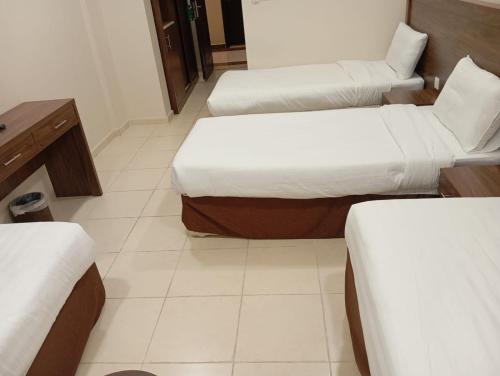 a room with three beds and a table and a desk at فندق الساعي Alsai Hotel in Al ‘Utaybīyah