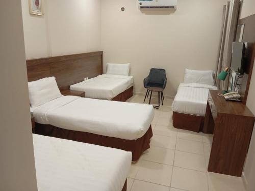 a room with three beds and a desk and a chair at فندق الساعي Alsai Hotel in Al ‘Utaybīyah