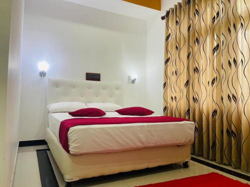 a bedroom with a bed with red pillows on it at Laaya Neem Dambulla in Dambulla