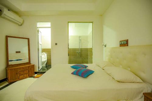 a bedroom with a bed with two pillows and a mirror at Laaya Neem Dambulla in Dambulla