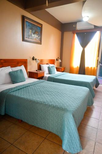 a hotel room with two beds and a window at Hotel Las Colinas in Fortuna