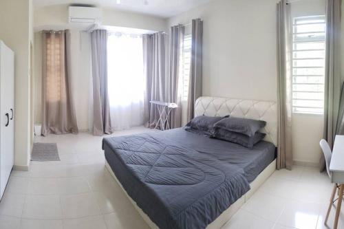 a bedroom with a large bed in a room with windows at Teratak Teratai Homestay- Corner in Semenyih