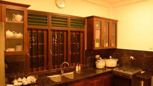 a kitchen with wooden cabinets and a counter top at Kurulu Villa Baddegama in Galle