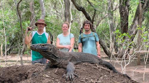 a group of three men standing next to a crocodile at Jhuna Komodo Homestay in Komodo