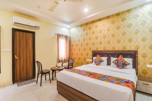 1 dormitorio con 1 cama grande, mesa y sillas en FabExpress Grand Inn, en Vibhuti Khand