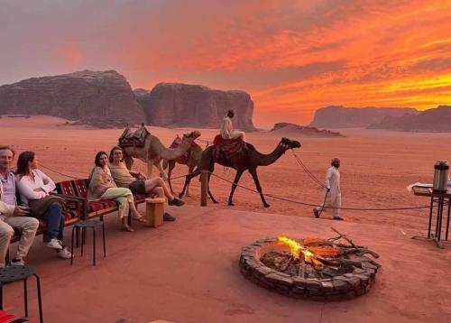 a group of people sitting around a fire in the desert at Tamim Luxury Camp in Wadi Rum