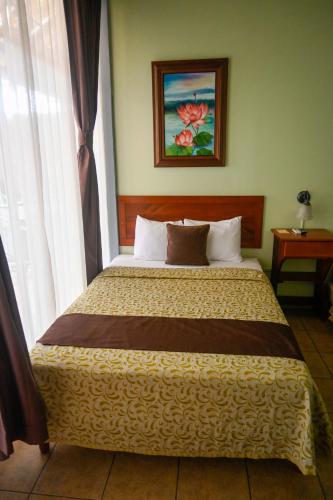 a bedroom with a bed in a room with a window at Hotel Las Colinas in Fortuna