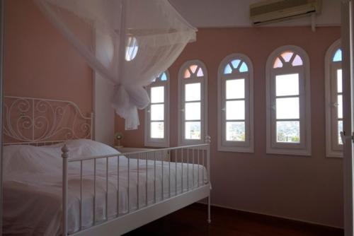 a bedroom with a white bed with four windows at Villa Dendron in Aghia Marina