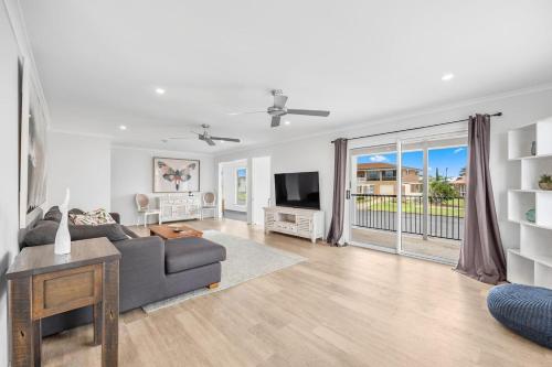 a living room with a couch and a tv at Hillcrest House - A Poolside Retreat on the Coast in Hervey Bay