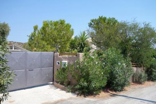 a fence in front of a house with trees and bushes at Villa Dendron in Aghia Marina