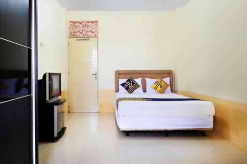 1 dormitorio con 1 cama y TV. en SPOT ON 2610 Zn Guest House en Makassar