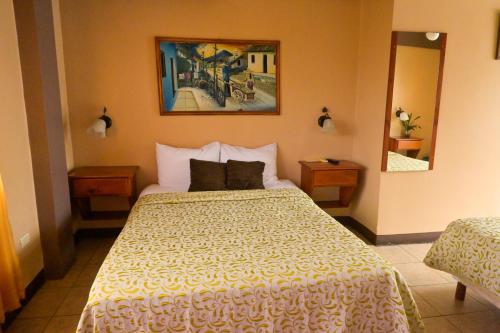 a bedroom with a large bed with a yellow blanket at Hotel Las Colinas in Fortuna
