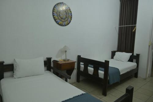 a room with two beds and a clock on the wall at Hotel Las Colinas in Fortuna