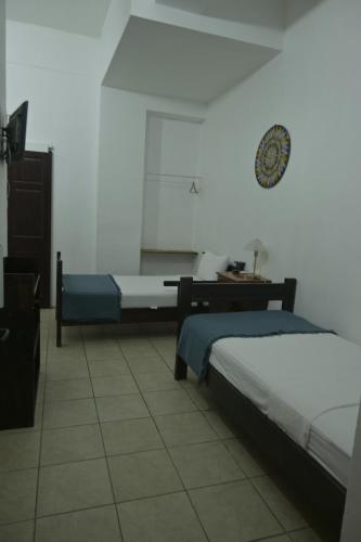 a bedroom with two beds and a clock on the wall at Hotel Las Colinas in Fortuna