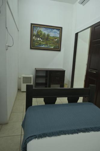 a bedroom with a bed and a picture on the wall at Hotel Las Colinas in Fortuna