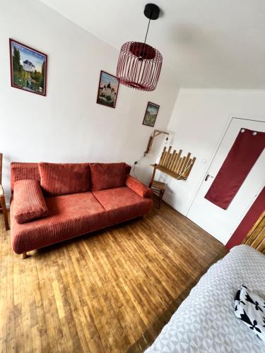 a living room with a red couch and a bed at Maison d'Hôtes Ty Belle in Saint-Guen