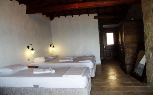 a room with two beds and a hallway with a door at Degirmen Konukevi in Gokceada Town