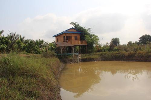 a house on the side of a river next to a lake at Kampot CoCo Homestays in Phumĭ Bœ̆ng Preăh (1)