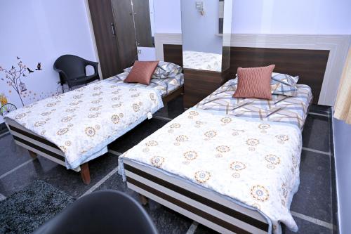 a room with two beds and a chair at Anyhour Stay in Gannavaram