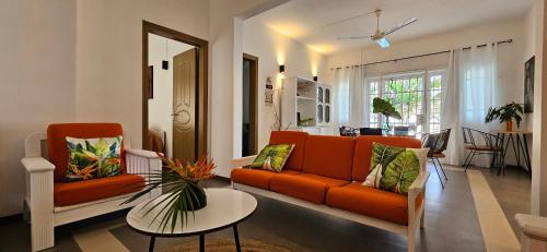a living room with an orange couch and a table at Ground Floor Apartment near Pereybere Beach in Pereybere