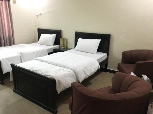 duas camas e uma cadeira num quarto em AK House Guest House em Islamabad