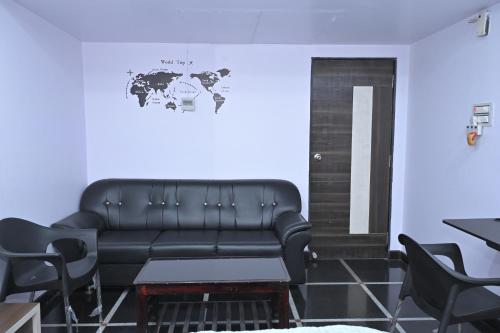 a black leather couch in a room with a map on the wall at Anyhour Stay in Gannavaram
