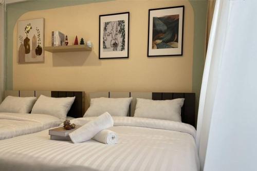 twee bedden met witte lakens in een slaapkamer met foto's aan de muur bij RB5: PrivateHouse 8pax,chatuchak,mrt,jodd fair in Ban Zong Katiam