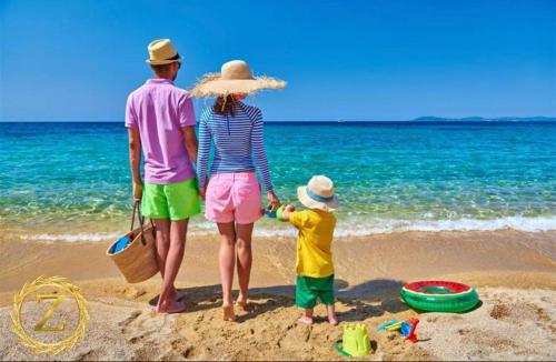 2 adultos y 1 niño parado en la playa en Boutique Villa with Rooftop Pool en Netanya