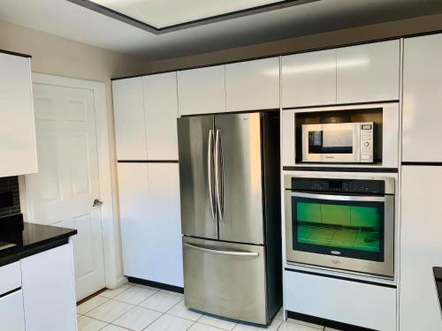 cocina con nevera de acero inoxidable y microondas en Burnaby lovely home, en Burnaby