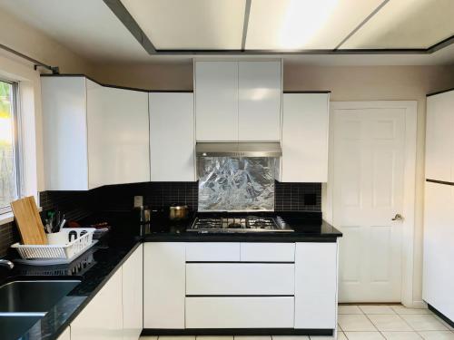 uma cozinha com armários brancos e um forno com placa de fogão em Burnaby lovely home em Burnaby