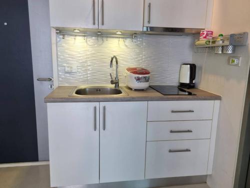 a kitchen with white cabinets and a sink at Grandblue condominium 205 in Ban Tha Fat