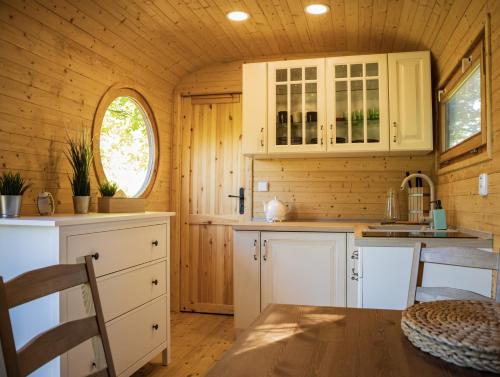 a kitchen with white cabinets and a table in a cabin at Maringotky Na Růžku in Nová Ves